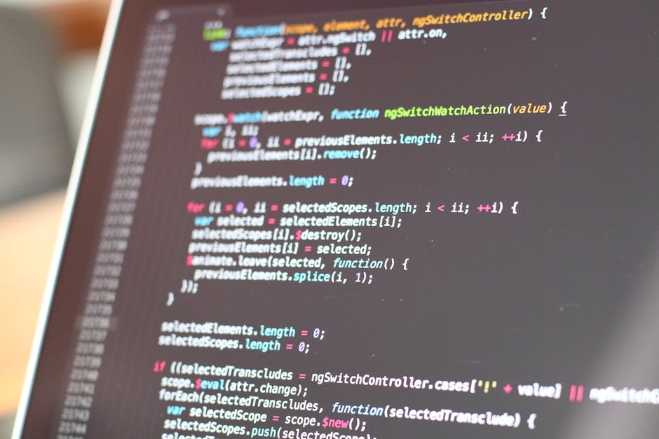 Close-up of a laptop keyboard and screen displaying lines of code with colorful syntax highlighting, with a blurred background. The keyboard features black keys with white symbols and a silver frame, 
